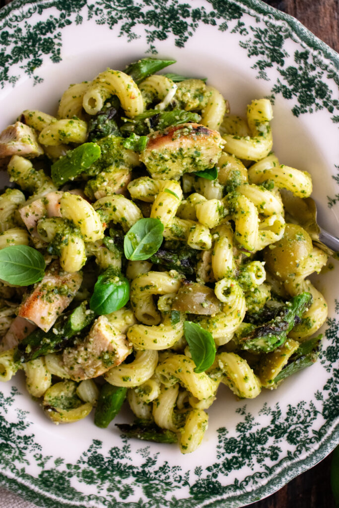 a bowl of pesto pasta salad with grilled chicken & asparagus