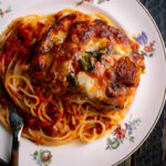 eggplant parmesan and spaghetti on a plate with tomato sauce