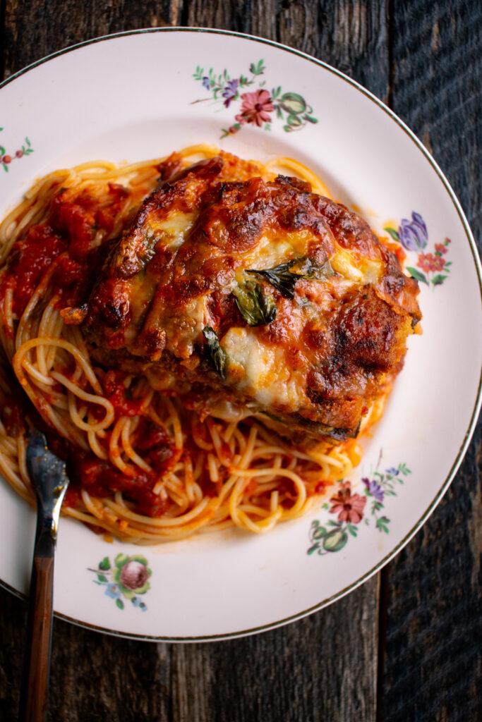 eggplant parmesan and spaghetti on a plate with tomato sauce