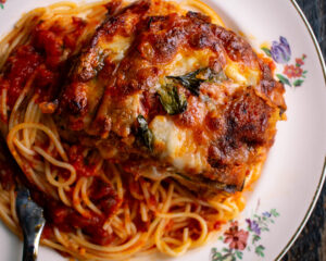 eggplant parmesan and spaghetti on a plate with tomato sauce