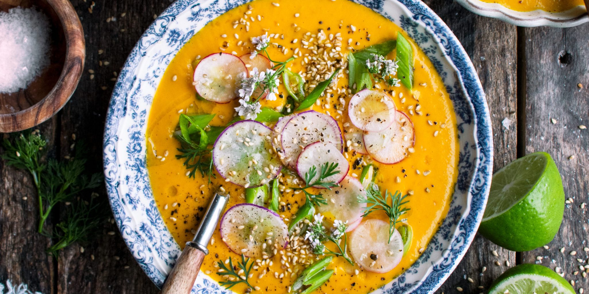 one bowl of Creamy Tahini Carrot Soup with radishes and green onions